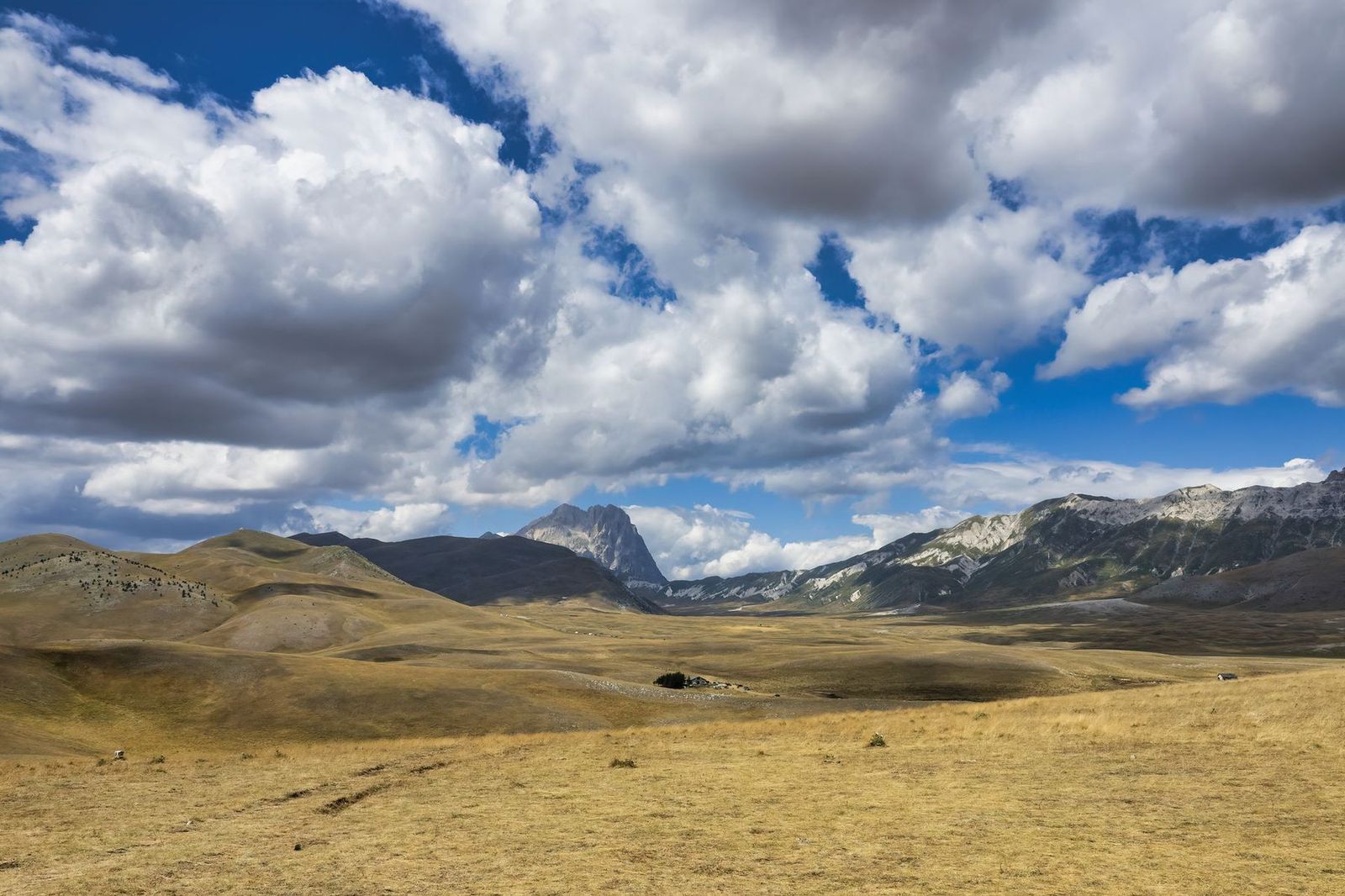 Le vaste plateau doré de Campo Imperatore, sous un grand ciel nuageux, avec le Corno Grande au loin.