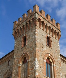 Détail de la tour d'angle crénelée du Castello Ducale di Crecchio, en brique et pierre, avec ses fenêtres géminées.