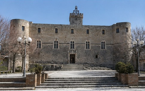 La façade principale du Castello Piccolomini di Capestrano, avec sa tour crénelée centrale et son grand escalier d'accès.