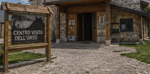 Illustration de l'entrée du Centro Visita dell'Orso à Villavallelonga, bâtiment en pierre et bois avec son panneau d'accueil.