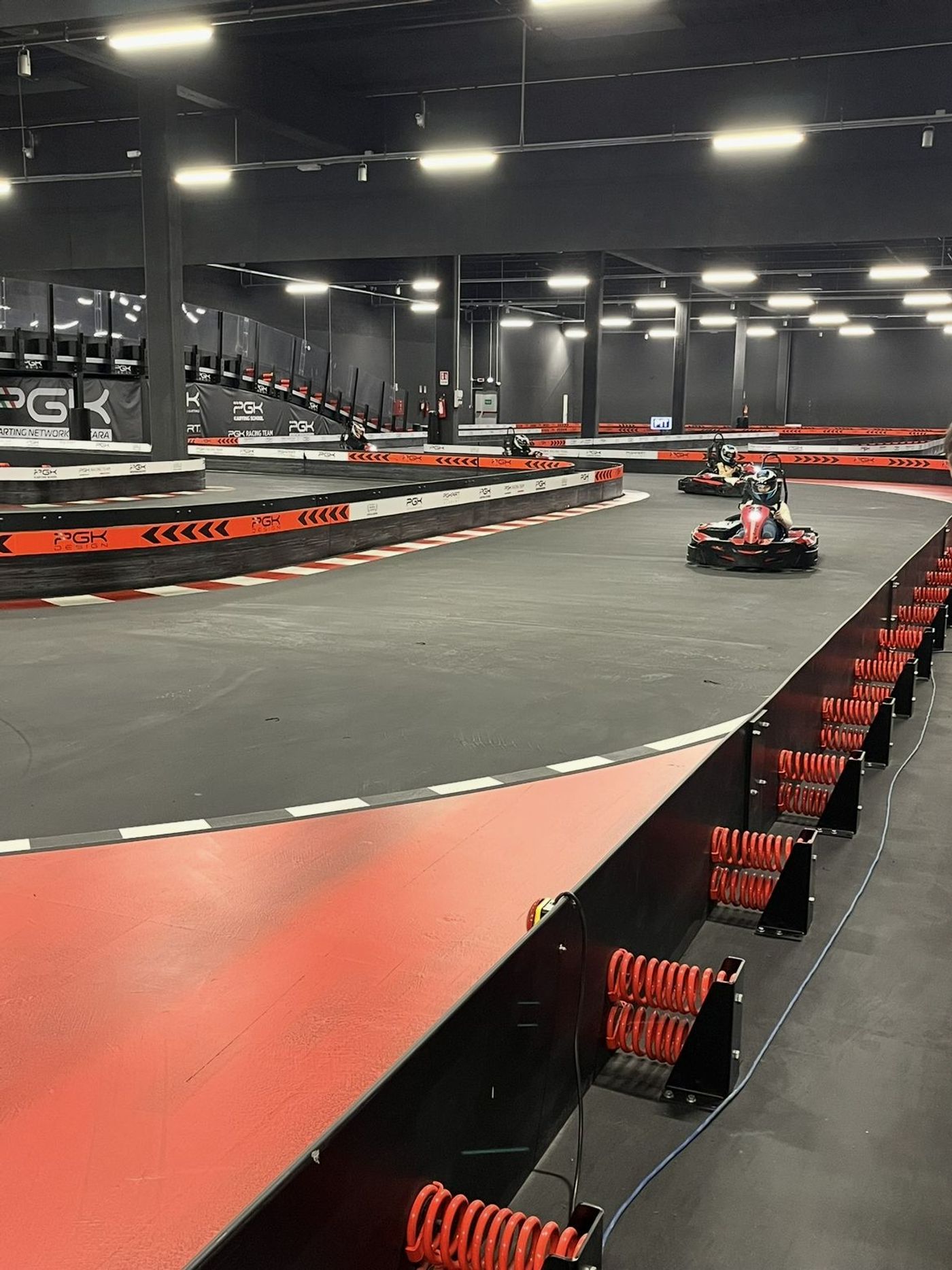La piste indoor d'E-Motion Karting Pescara (PGK Karting Network), deux karts en pleine course dans un virage protégé par des barrières à ressorts.