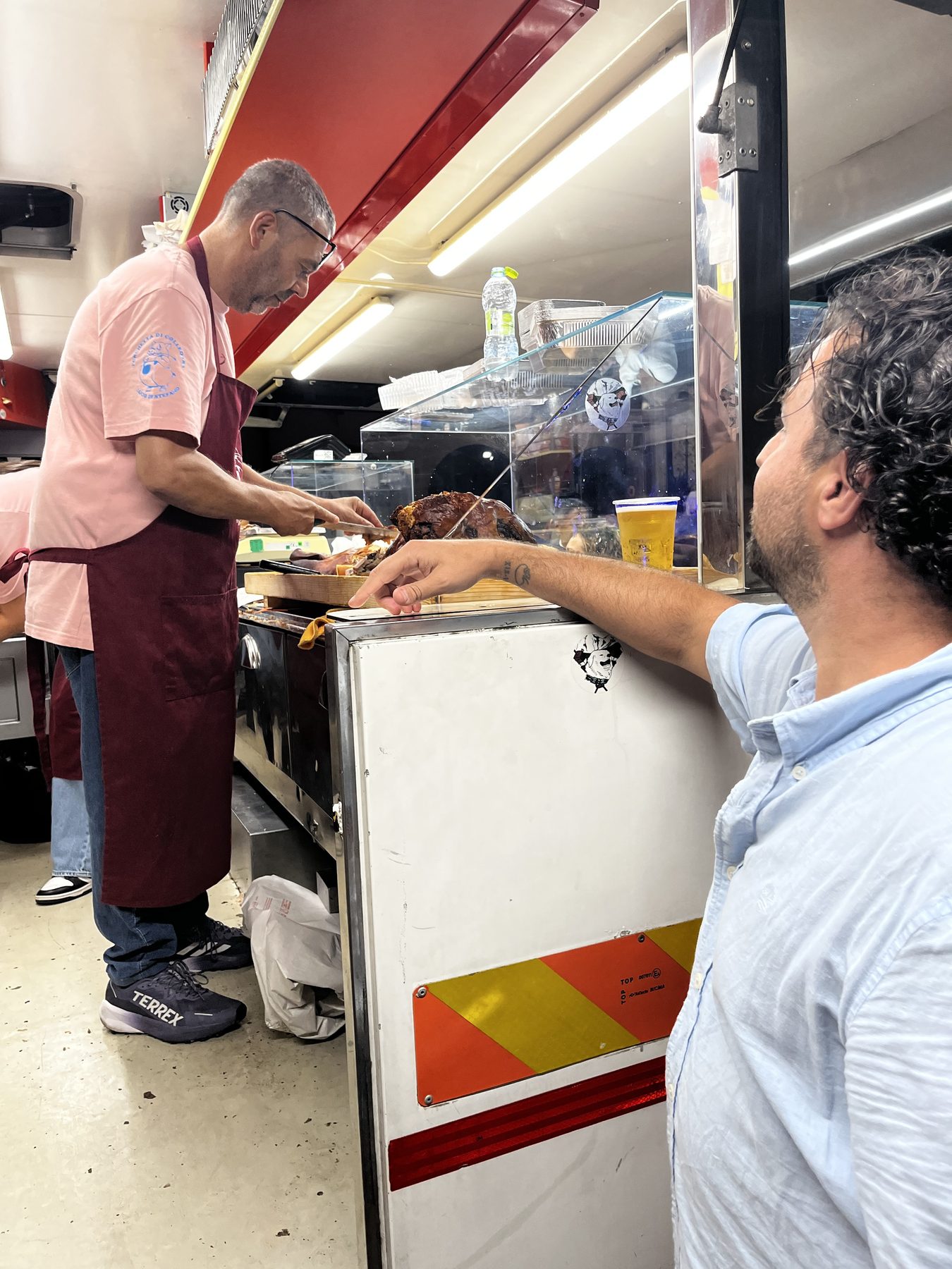 Lucio Di Stefano découpe une porchetta entière devant un client, au camion Porchetta di Colledara.