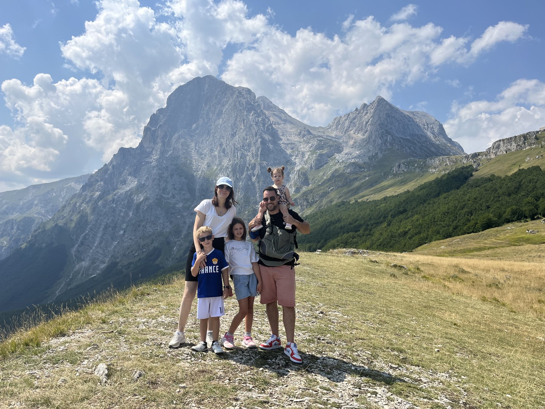 Une famille avec trois enfants pose dans la prairie de Prati di Tivo, face aux sommets du Gran Sasso.