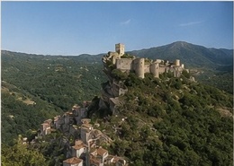 Le Castello di Roccascalegna dominant le village perché à ses pieds, collines boisées environnantes.
