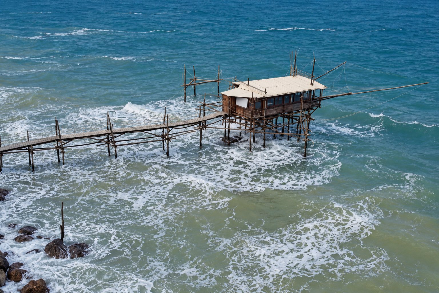 Illustration du Trabocco Trave à Vasto : sa passerelle sur pilotis et sa cabane au-dessus d'une mer agitée.