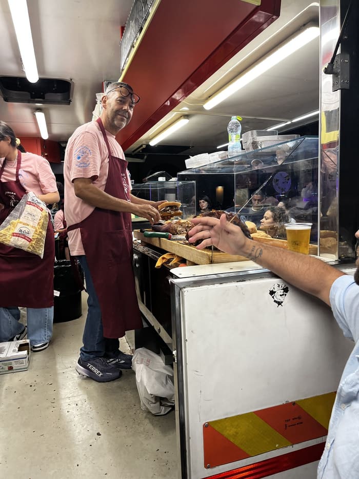 Lucio Di Stefano prépare un panino con la porchetta au comptoir de son camion.