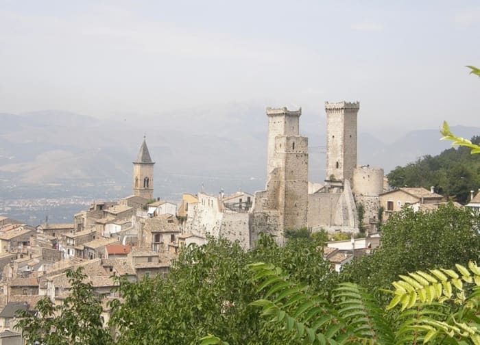 Les deux tours en ruine du Castello Caldora dominant les toits de Pacentro, avec le clocher de Santa Maria Maggiore au premier plan.